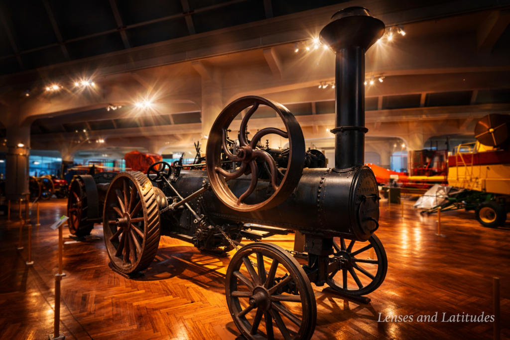 Antique steam tractor displayed indoors with large metal wheels and warm museum lighting