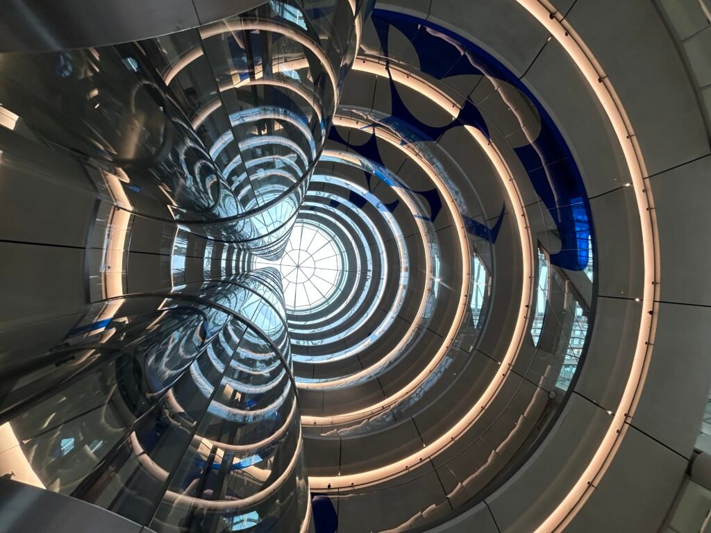 Modern architectural interior with sweeping circular lines and reflective glass viewed from below